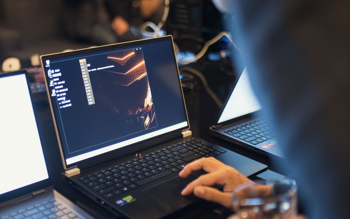 Hands working at a laptop in an office