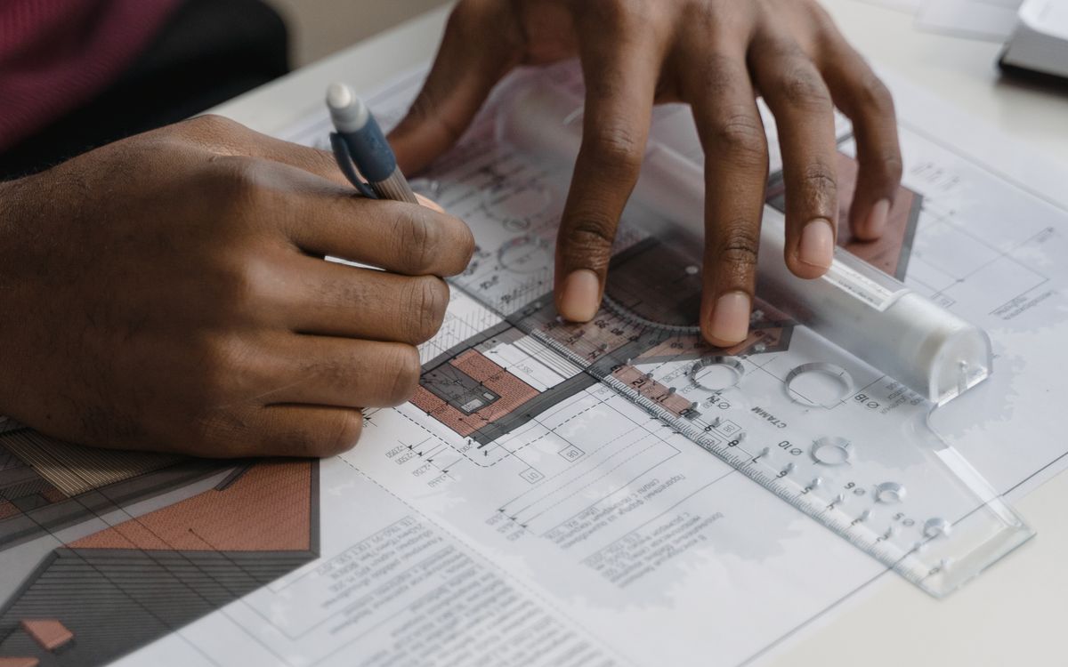 Hands drafting a technical drawing with a ruler