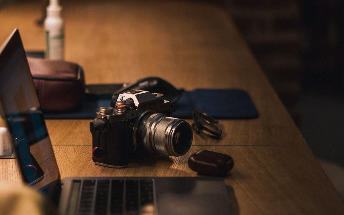 Camera and laptop on a wooden desk
