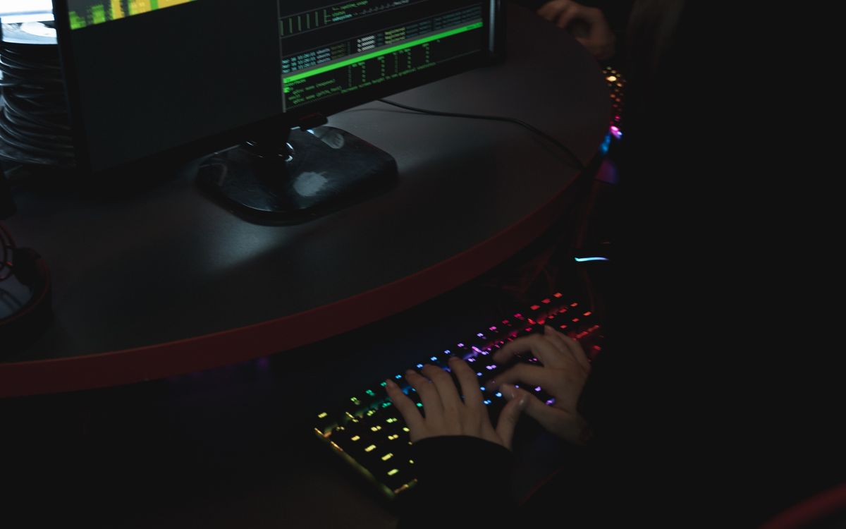 Person typing at a computer with illuminated screens